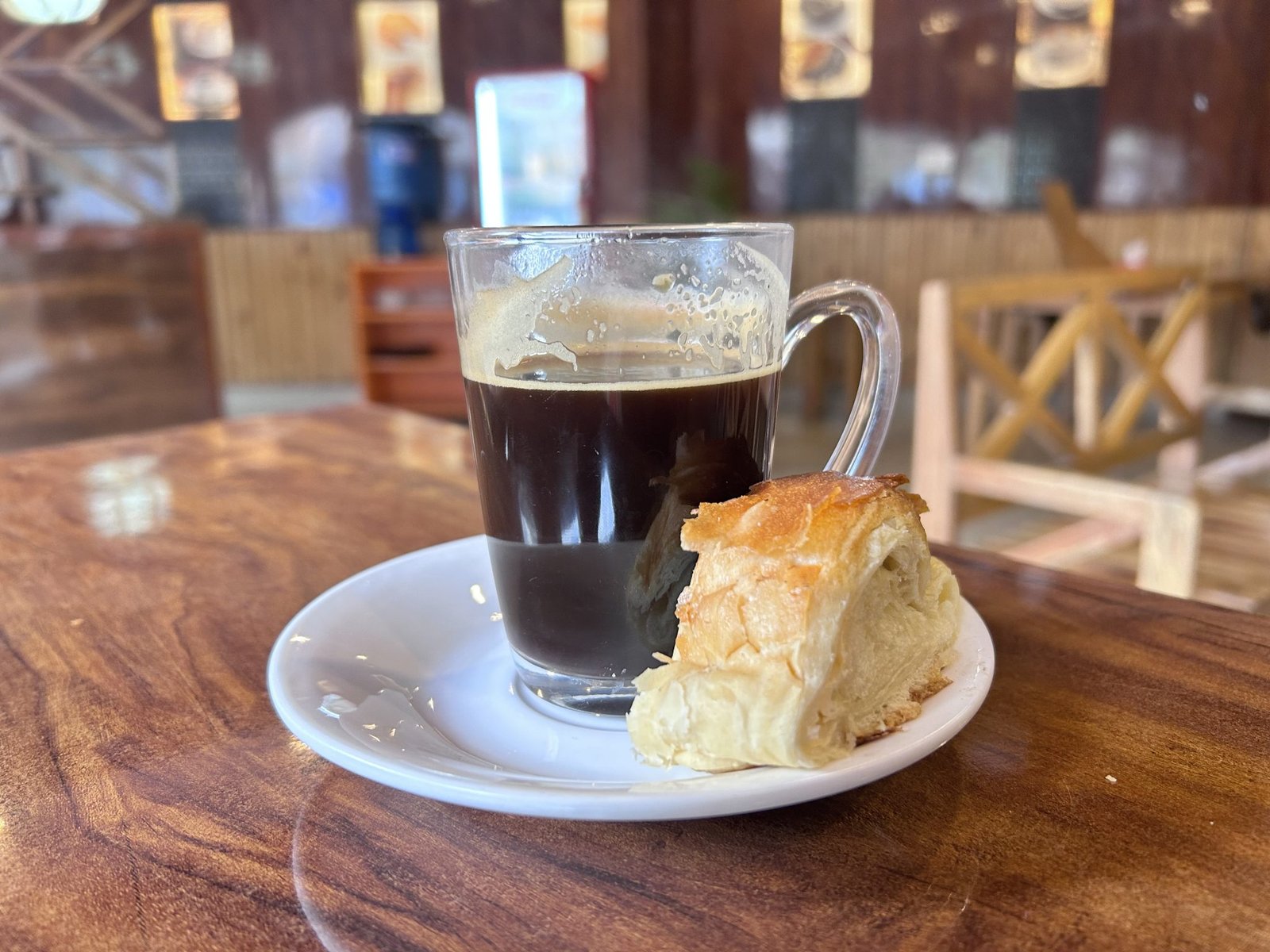 a glass of Americano coffee and a pastry on a plate