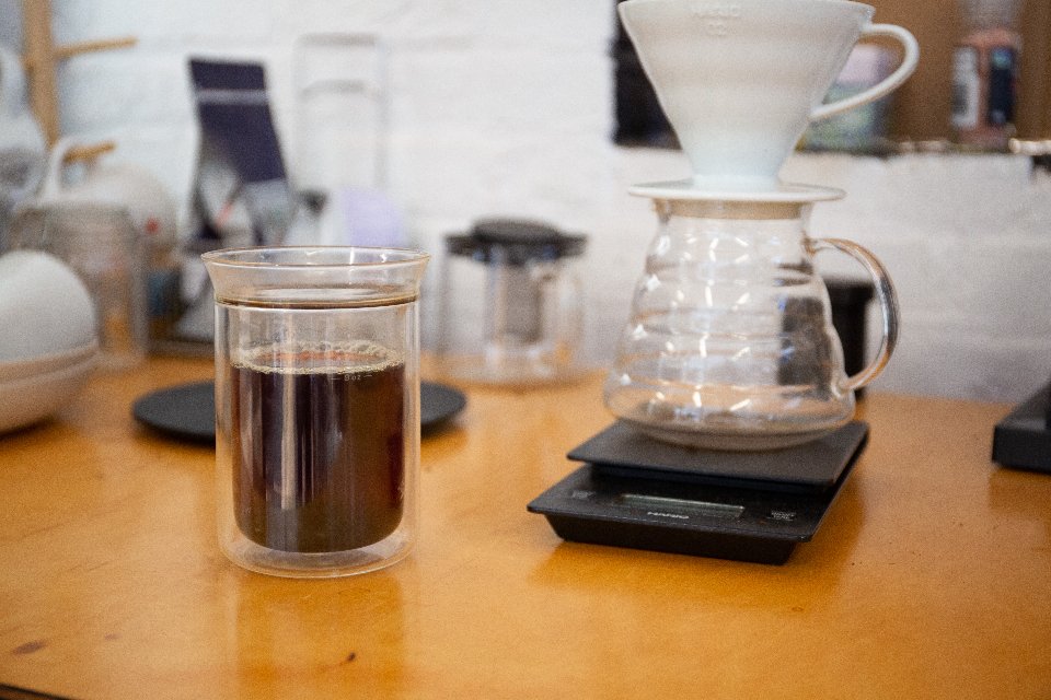 a glass cup with coffee in it next to a pour over nuanced cup