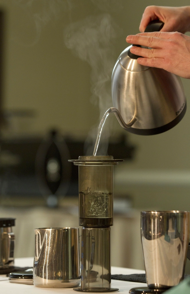 a person pouring liquid into an aeropress